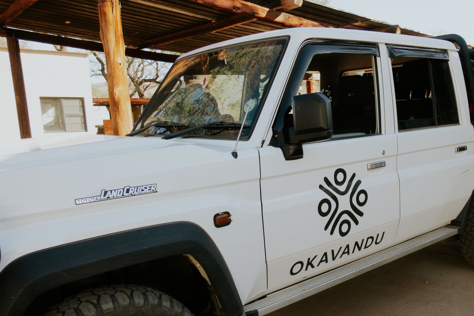 Der Land Cruiser mit dem Okavandu-Logo unter dem Holzcarport.