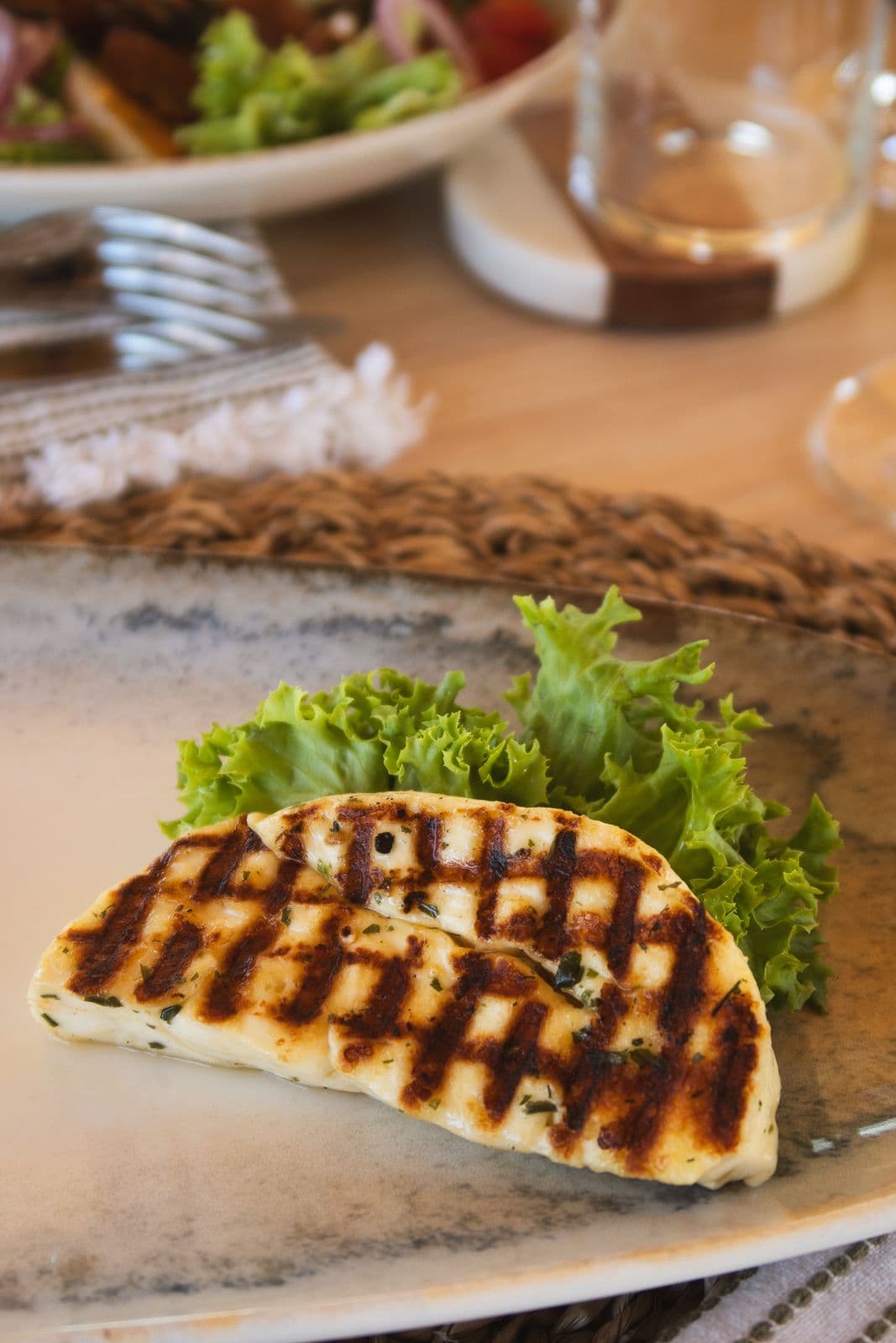 Gegrillter Halloumi mit Grillmuster auf einem Salatblatt.