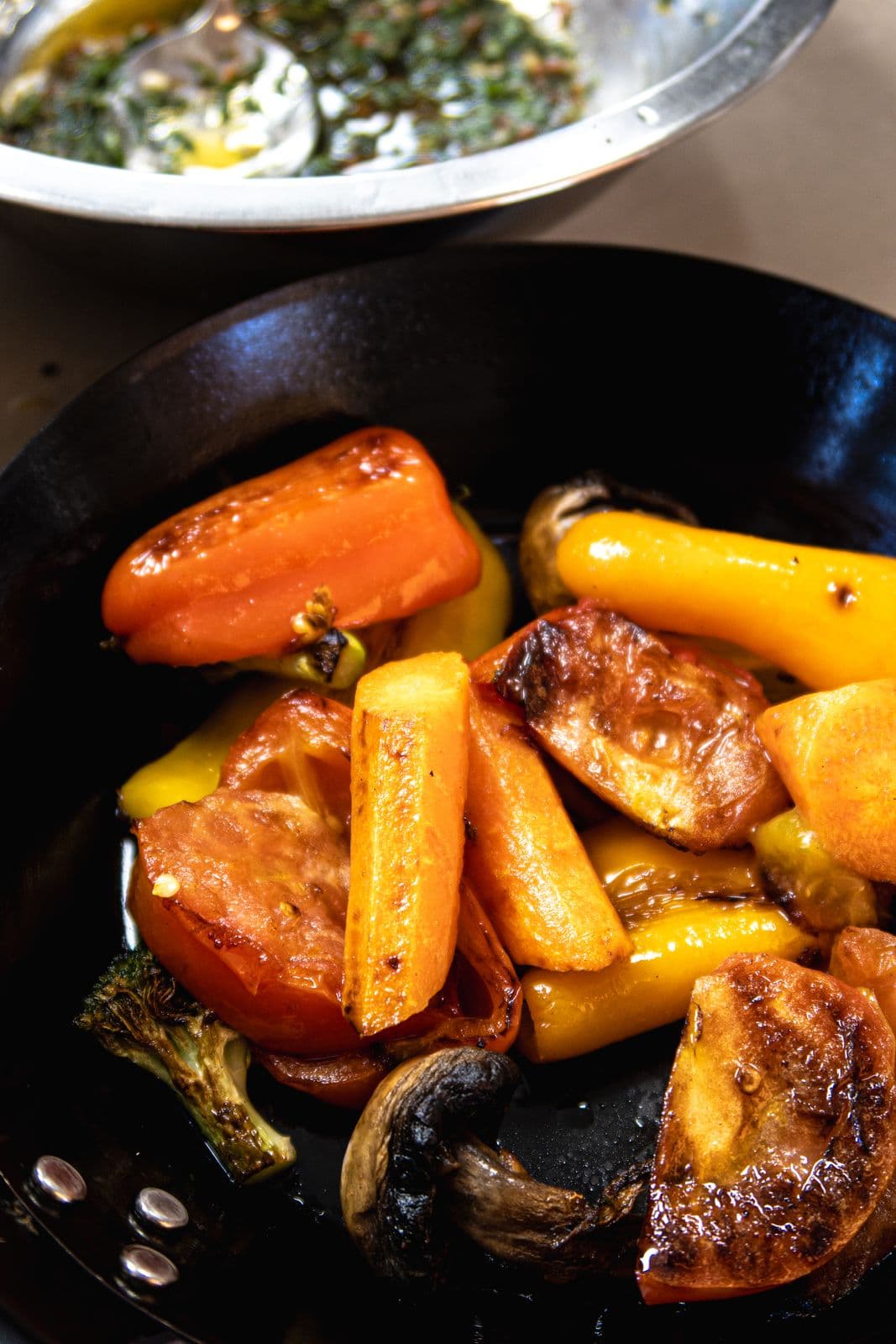 Geröstete Paprika, Karotten und Tomaten in einer gusseisernen Pfanne.