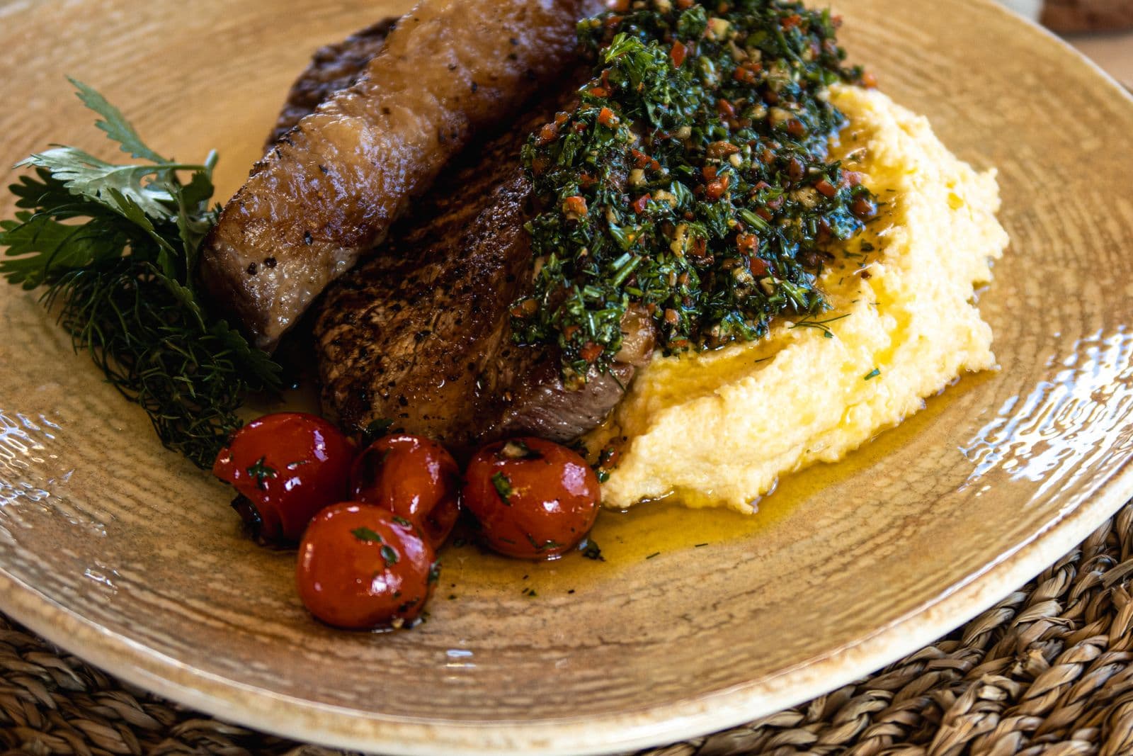 Rindersteak mit grüner Kräutersauce auf Kartoffelpüree, dazu Kirschtomaten.
