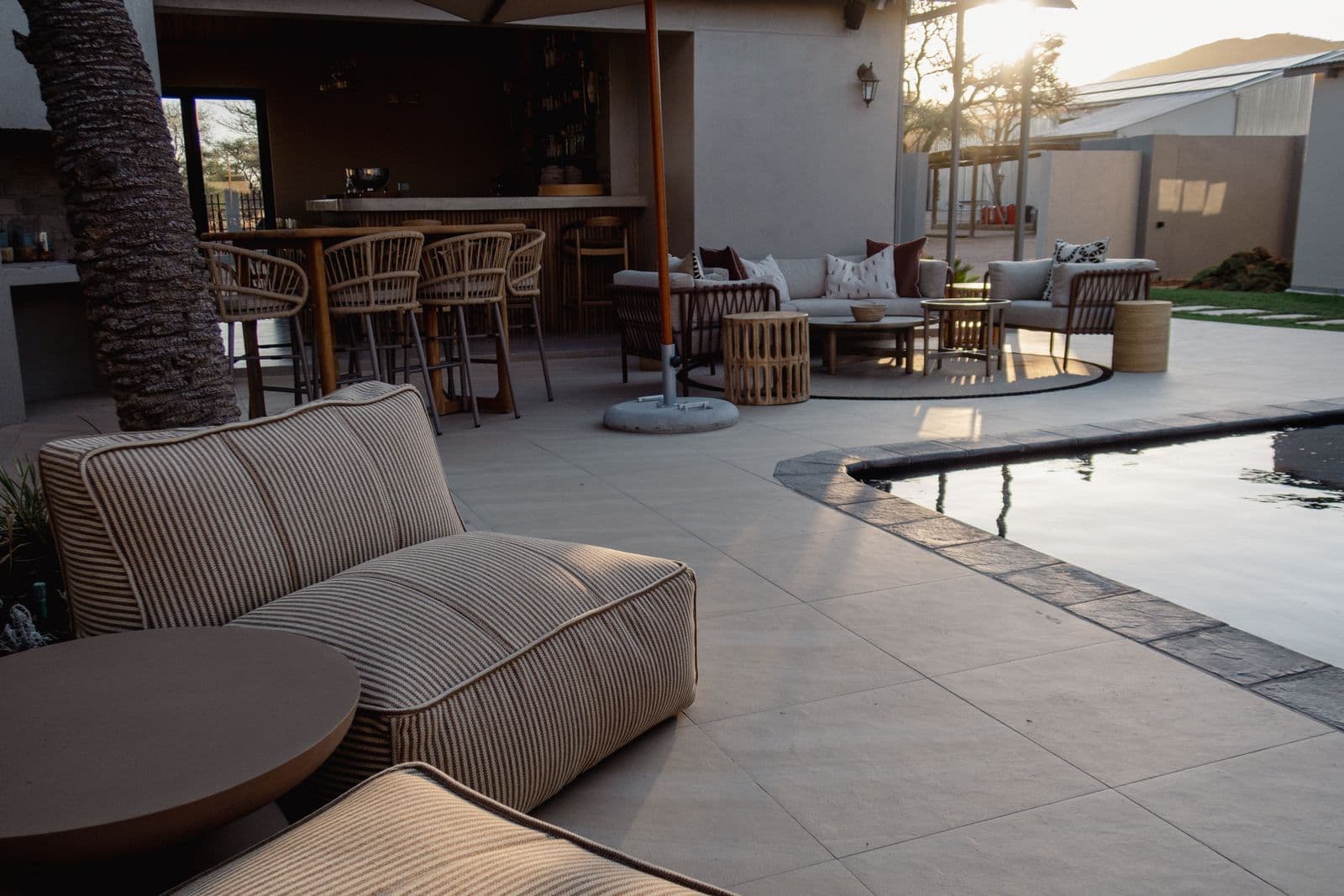 Ein gestreiftes Loungesofa am Pool, dahinter die Bar der Lapa.
