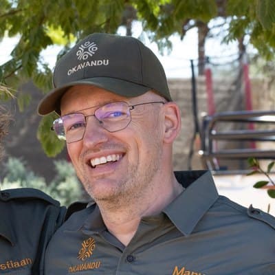 Manuel Drescher mit Okavandu-Kappe und Brille, lachend.