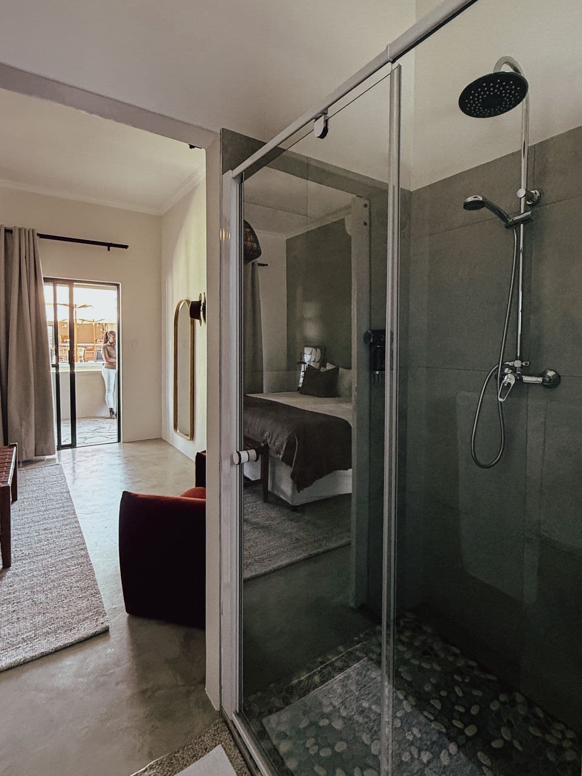 Regendusche hinter Glas, durch die Tür der Blick ins Zimmer.