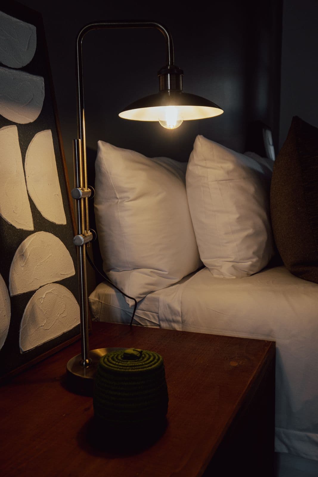 Nachttisch am Abend mit brennender Messinglampe und grünem Körbchen.