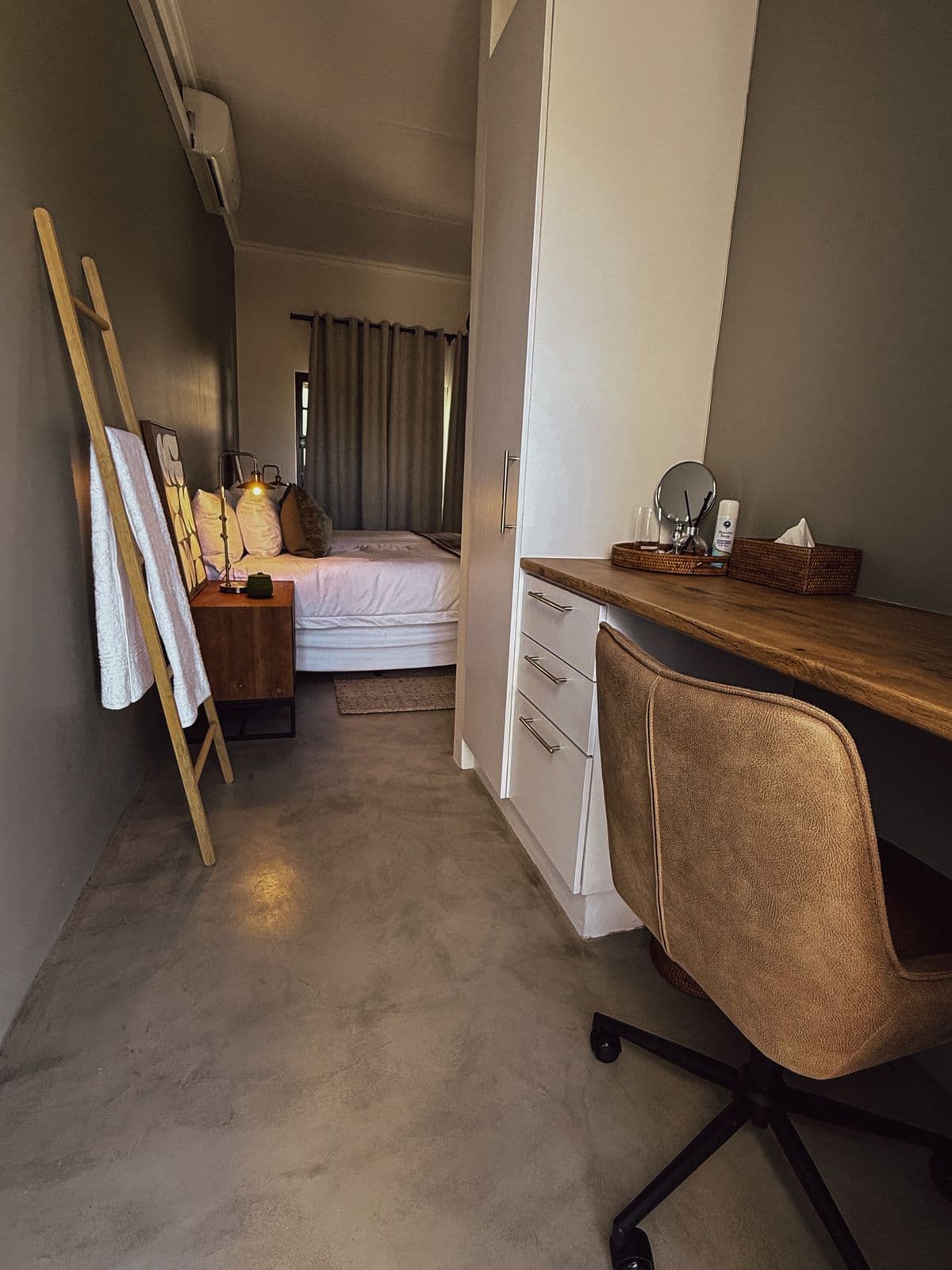 Schreibtisch mit Lederstuhl, dahinter der Blick ins Schlafzimmer.