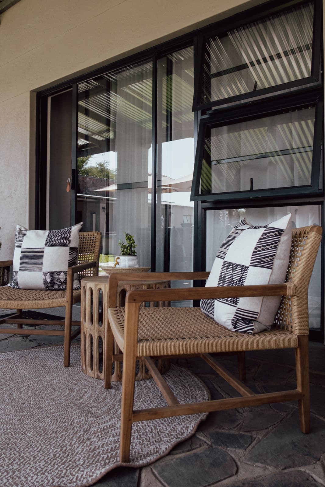 Die Terrasse vor dem Zimmer mit zwei Holzsesseln und rundem Teppich.