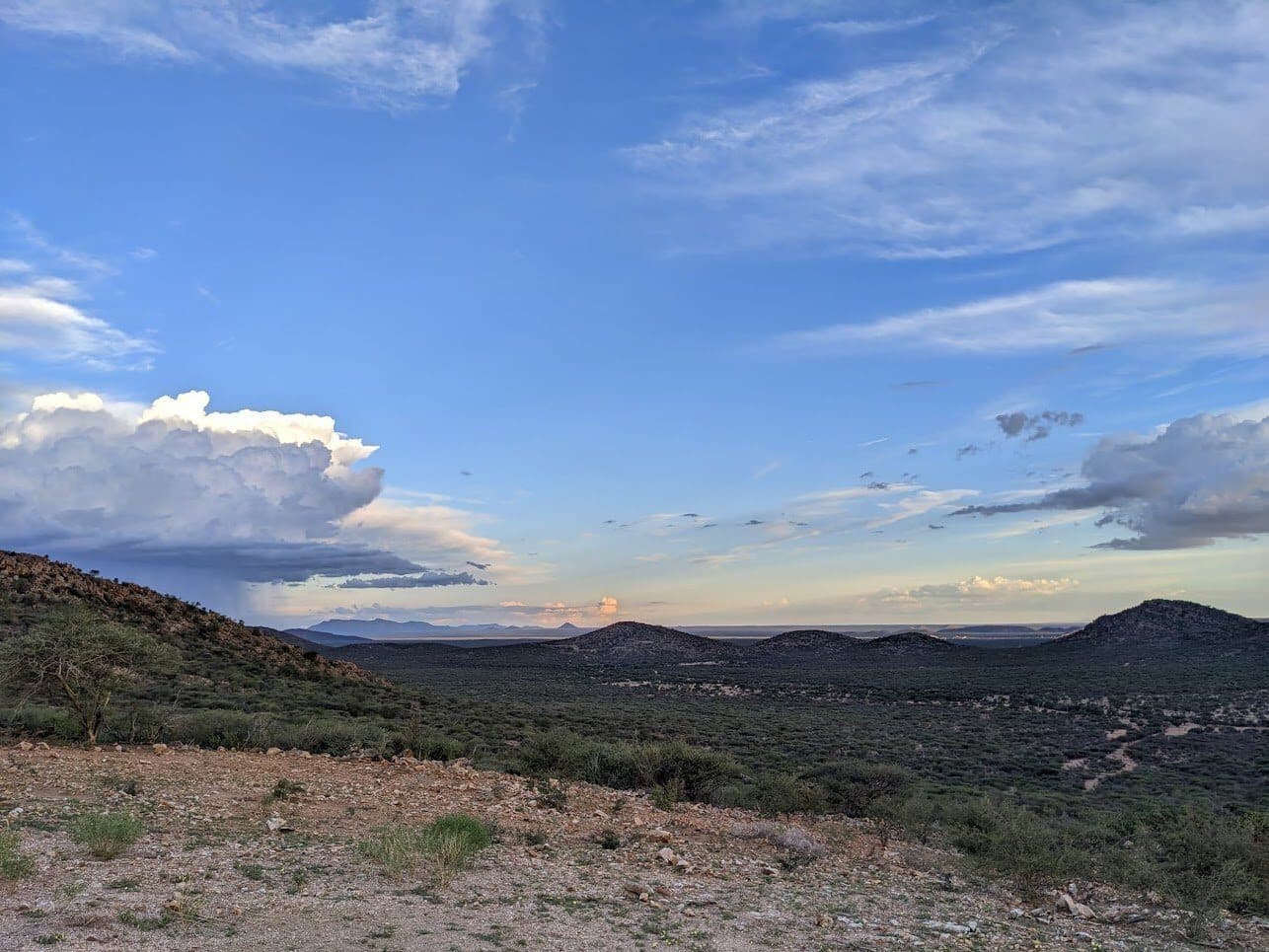 Weite Landschaft mit Bergen und Wolken am späten Nachmittag.