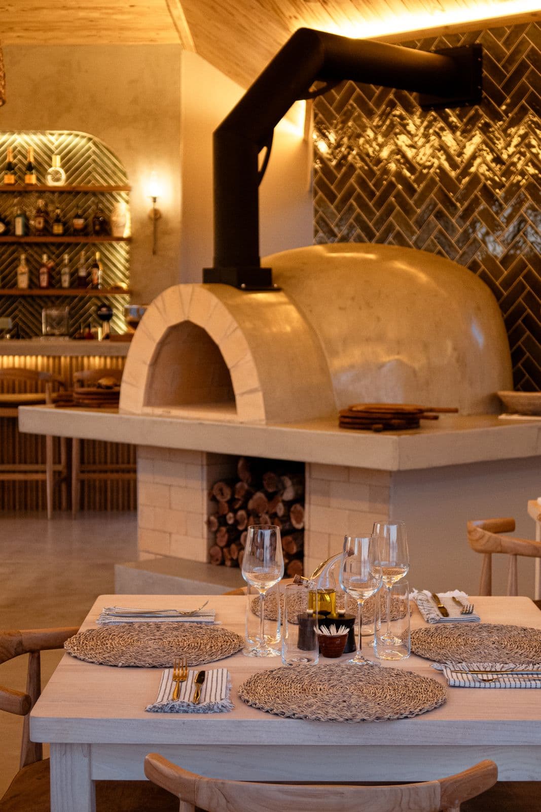 Der Pizzaofen der Lapa mit gemauerter Kuppel, davor ein gedeckter Tisch mit Gläsern.