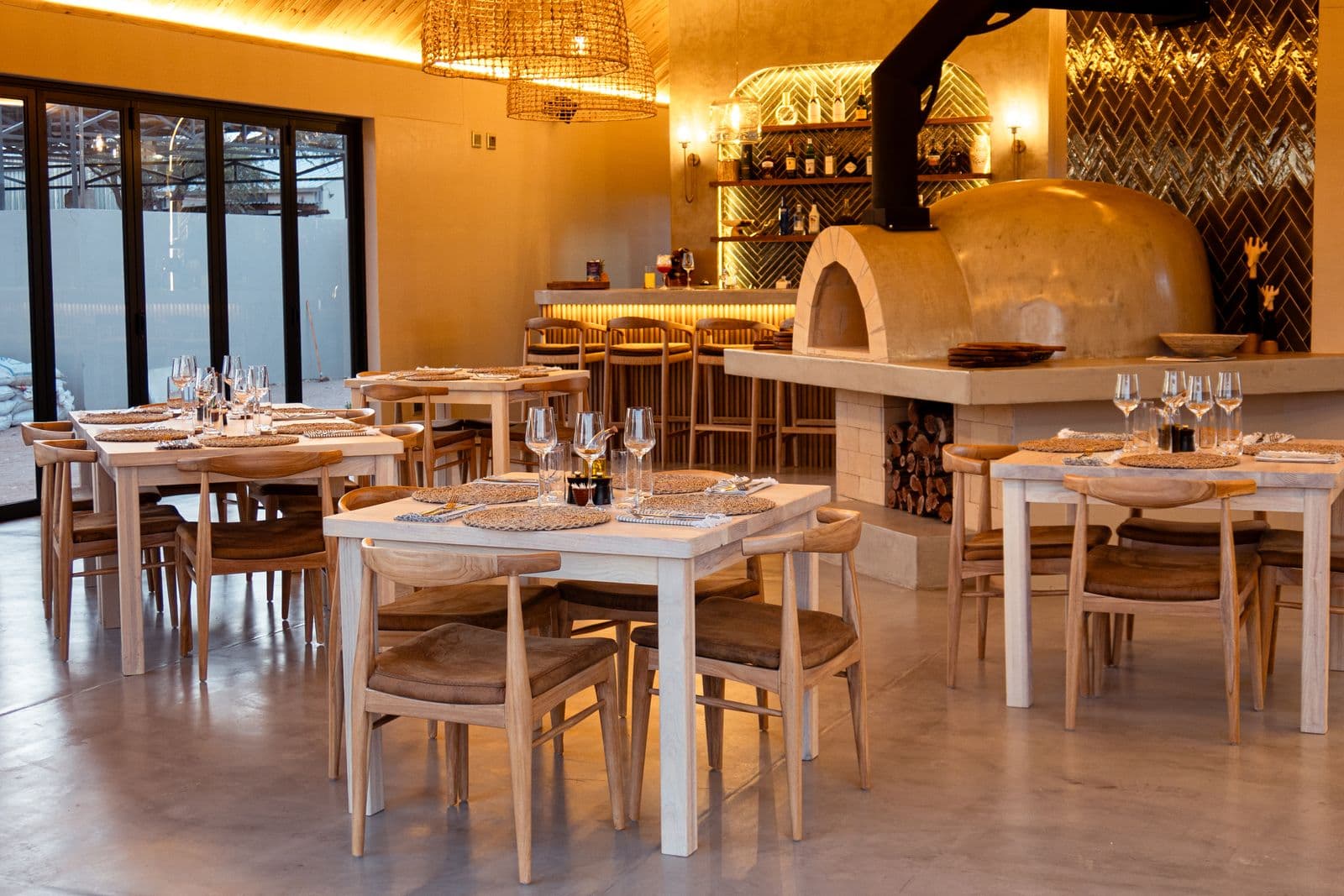 Das Restaurant in der Lapa am Abend: gedeckte Tische, dahinter der Pizzaofen und die beleuchtete Bar.